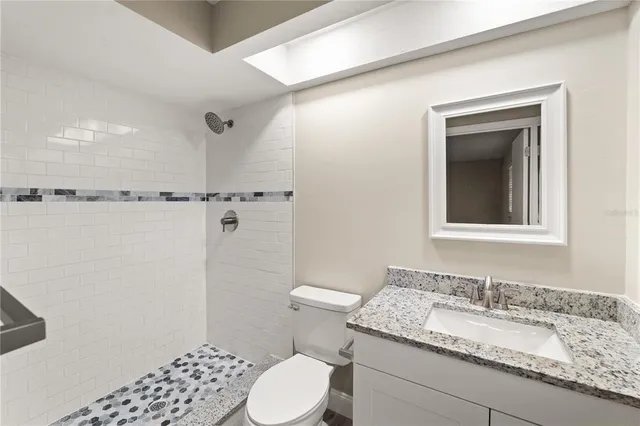 a bathroom with a granite countertop sink toilet and shower