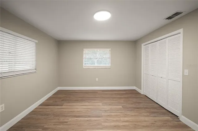 an empty room with wooden floor and windows