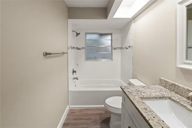 a bathroom with a granite countertop sink a toilet and shower