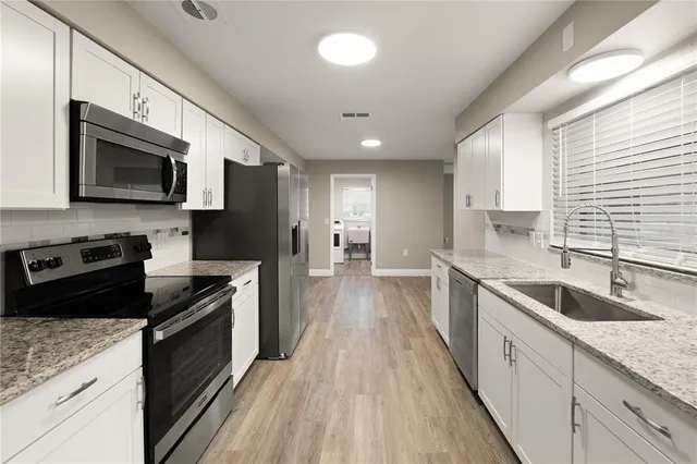 a large kitchen with stainless steel appliances granite countertop a stove a sink and a microwave