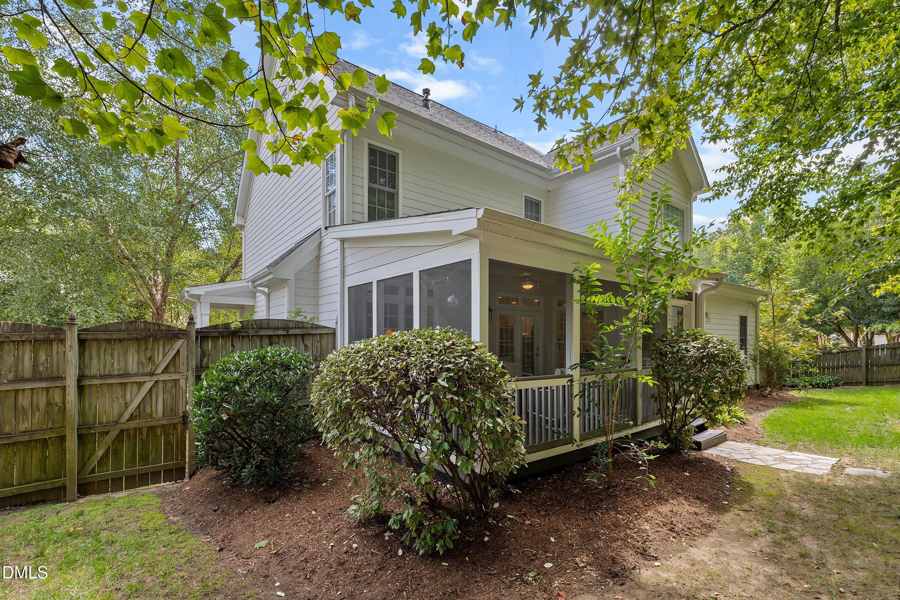 3914 Sterling Ridge Lane Durham, NC 27707 - Photo 56 of 66 White siding exterior featuring a screened porch with white railings, mature perimeter trees, and a wooden privacy fence