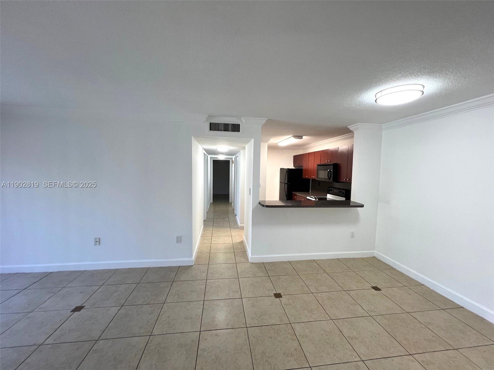 15550 Southwest 80th Street, Unit E101 Miami, FL 33193 - Photo 5 of 21 a view of a refrigerator in kitchen and an empty room