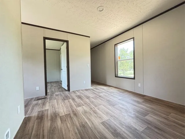 an empty room with wooden floor closet and windows