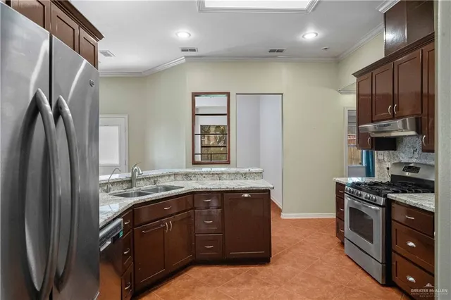a kitchen with stainless steel appliances granite countertop a stove a sink and a refrigerator