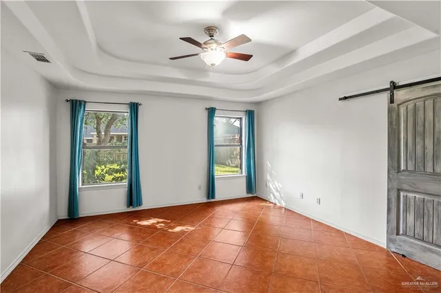 a view of an empty room with window and chandelier fan