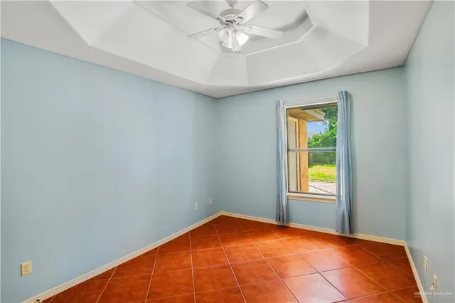an empty room with a chandelier fan and windows