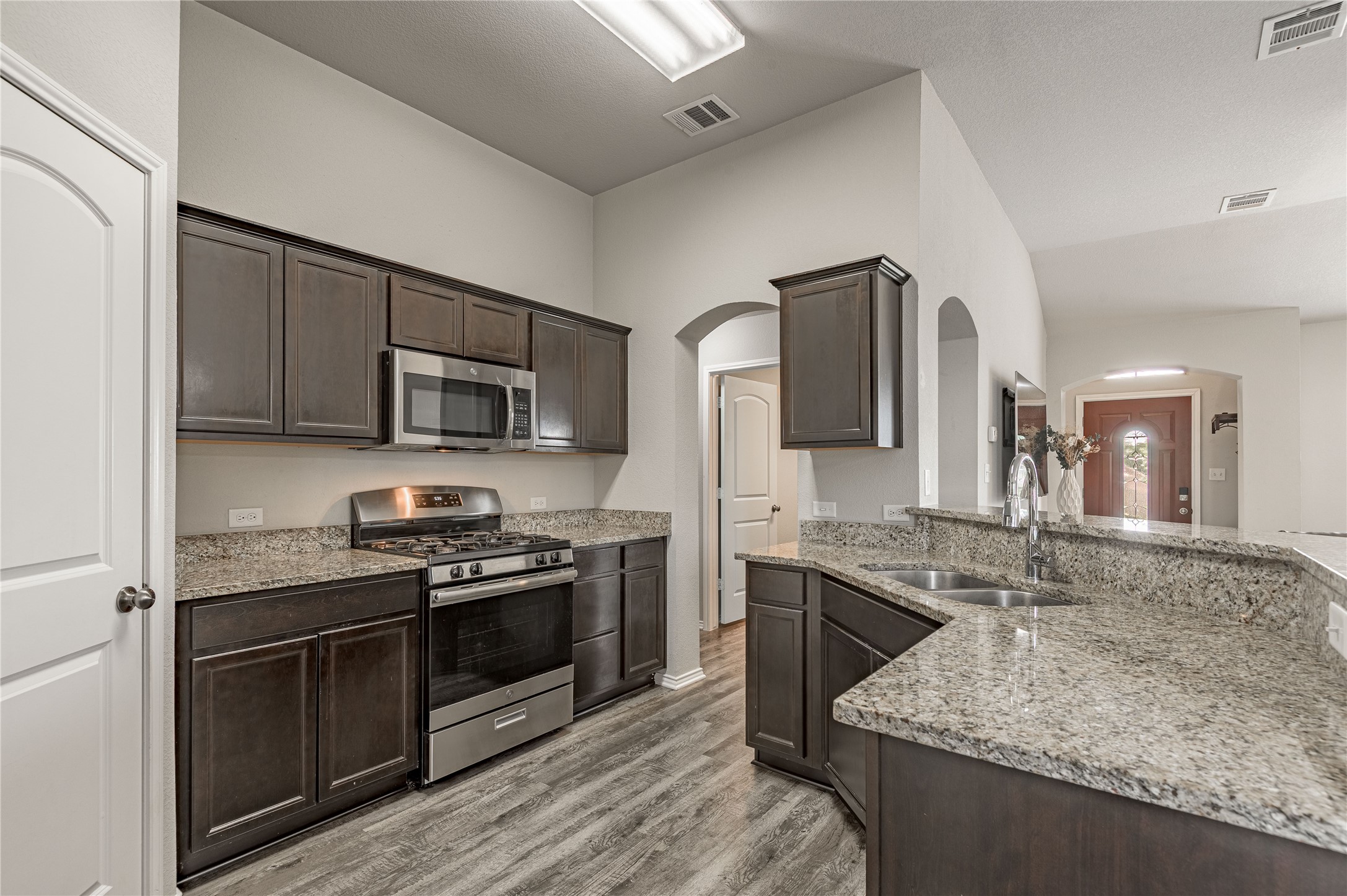 133 Bates Court Huntsville, TX 77320 - Photo 8 of 31 a kitchen with stainless steel appliances granite countertop a stove top oven a sink dishwasher a refrigerator and a microwave oven with wooden floor