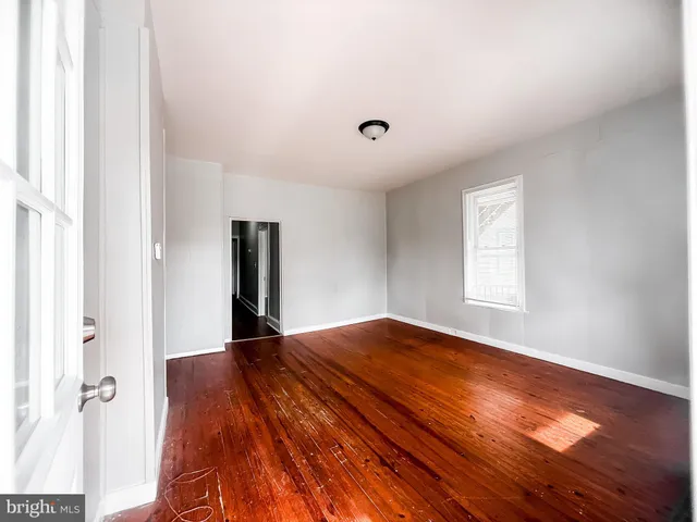 a view of empty room with window and wooden floor