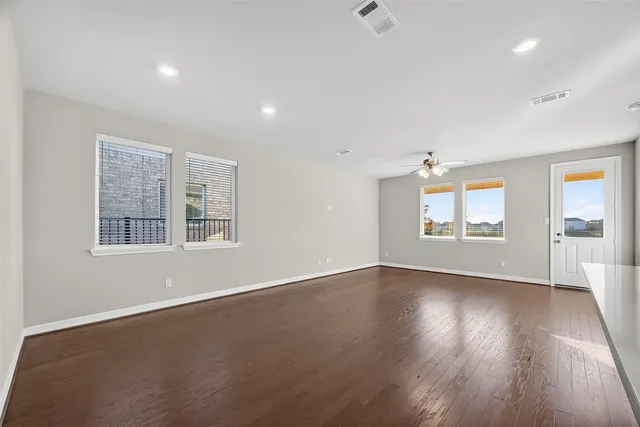 an empty room with wooden floor and windows