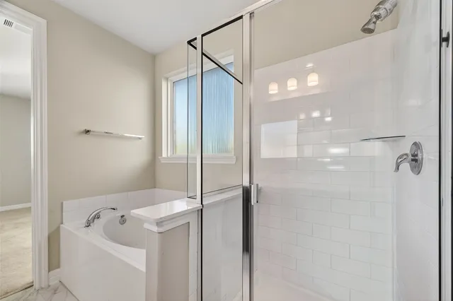 a bathroom with a tub a mirror and a shower