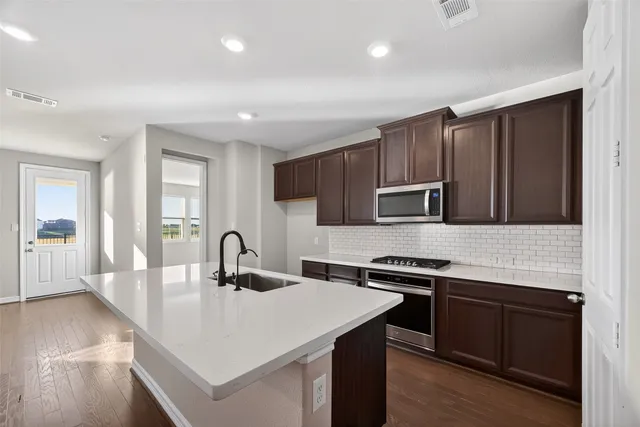 a kitchen with kitchen island granite countertop a stove and a sink