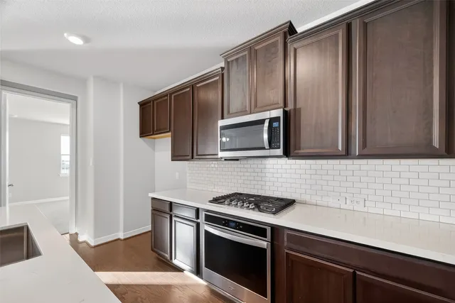 a kitchen with stainless steel appliances granite countertop a sink stove and microwave