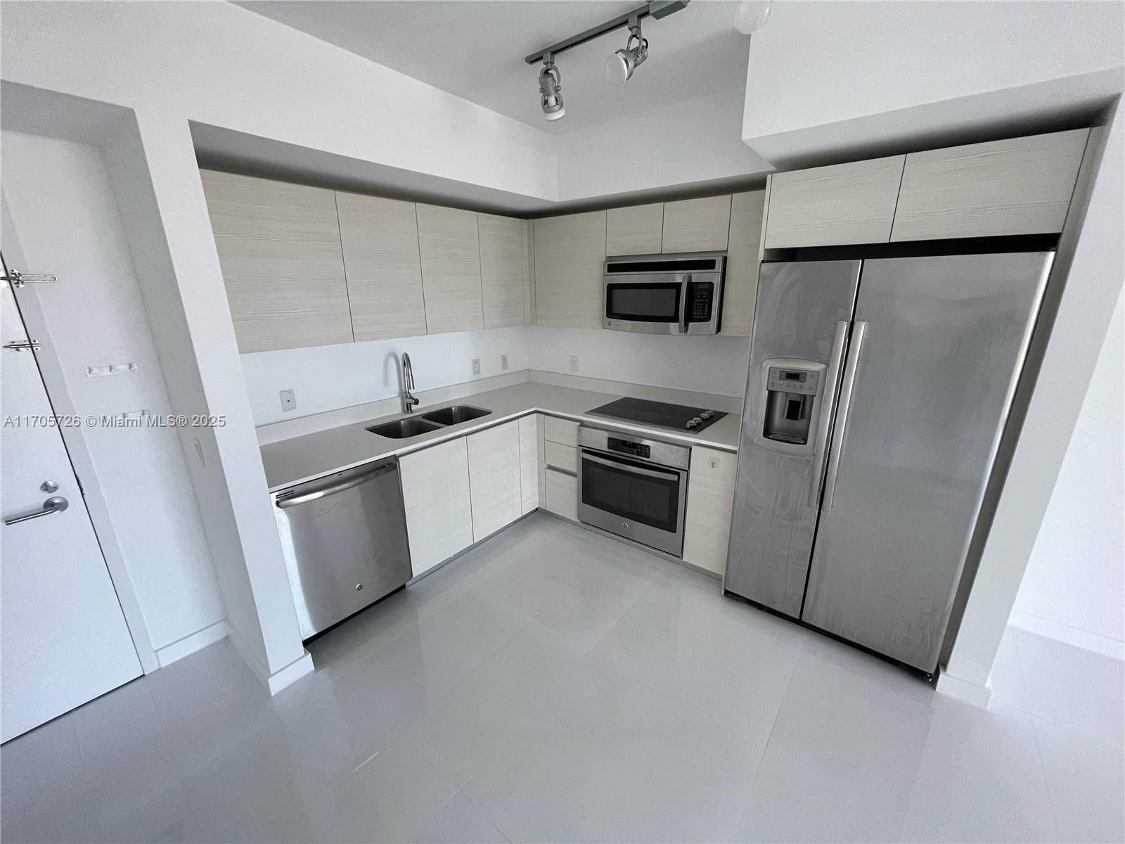 4250 Biscayne Boulevard, Unit 1104 Miami, FL 33137 - Photo 3 of 31 a kitchen with white cabinets sink and stainless steel appliances