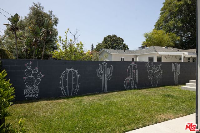a view of a backyard with large tree and wooden fence