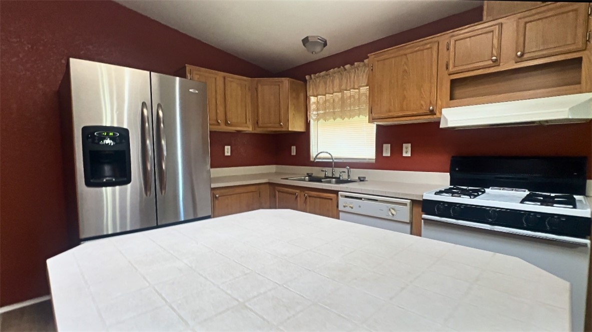 3746 Bouse Road Golden Valley, AZ 86413 - Photo 11 of 53 Kitchen with stainless steel fridge, range with gas cooktop, under cabinet range hood, light countertops, and lofted ceiling
