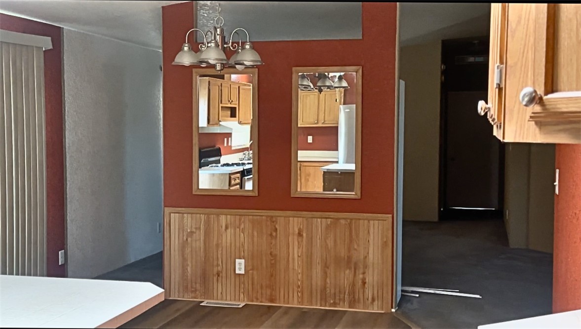 3746 Bouse Road Golden Valley, AZ 86413 - Photo 23 of 53 Unfurnished dining area featuring dark wood finished floors, a wainscoted wall, and a chandelier