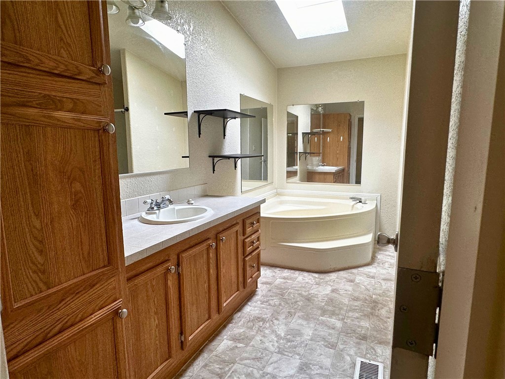 3746 Bouse Road Golden Valley, AZ 86413 - Photo 39 of 53 Bathroom featuring a skylight, vanity, a textured wall, and a garden tub