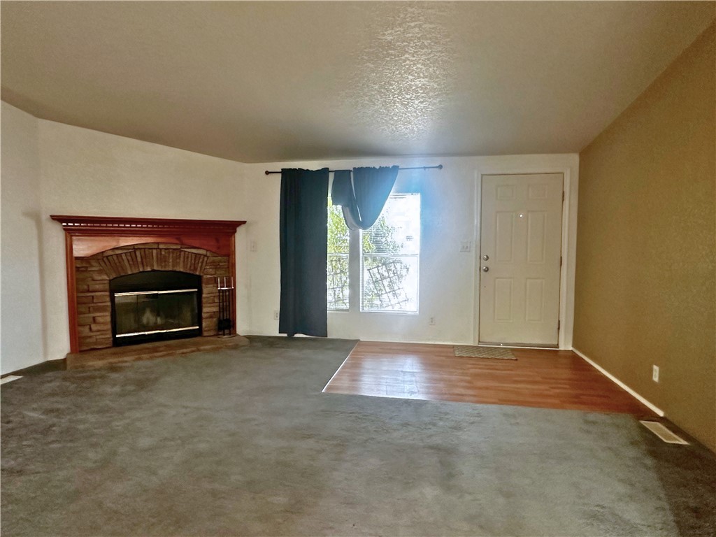 3746 Bouse Road Golden Valley, AZ 86413 - Photo 4 of 53 Unfurnished living room with a glass covered fireplace, wood finished floors, a textured ceiling, and carpet flooring