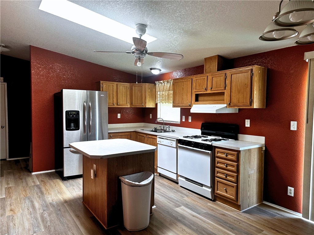 3746 Bouse Road Golden Valley, AZ 86413 - Photo 7 of 53 Kitchen with a textured wall, white appliances, a textured ceiling, light countertops, and light wood-style flooring