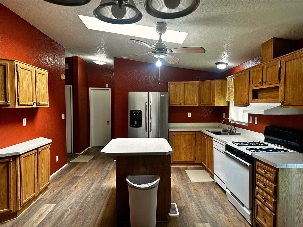 3746 Bouse Road Golden Valley, AZ 86413 - Photo 8 of 53 Kitchen with white appliances, vaulted ceiling, brown cabinetry, a center island, and wood finished floors
