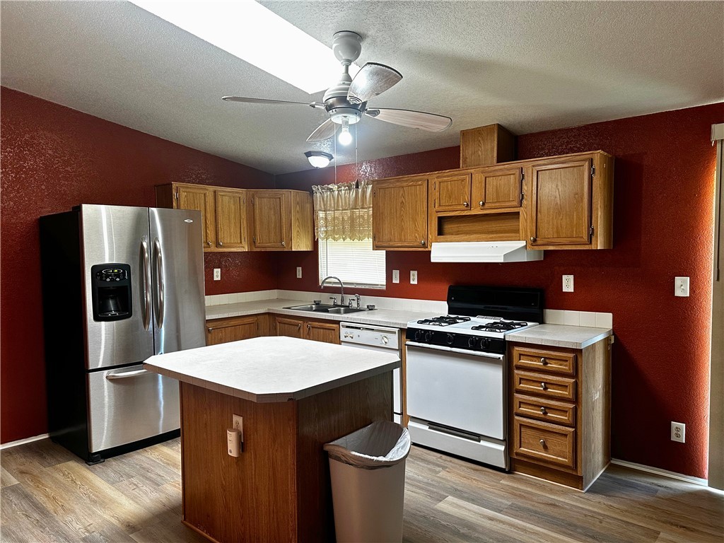 3746 Bouse Road Golden Valley, AZ 86413 - Photo 10 of 53 Kitchen with a textured wall, white appliances, light wood-style floors, light countertops, and a ceiling fan