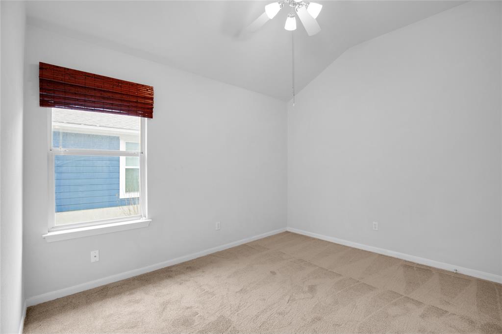 281 Hutton Kyle, TX 78640 - Photo 31 of 37 A window with warm bamboo blinds complements a room featuring high vaulted ceilings and soft carpeted floors.