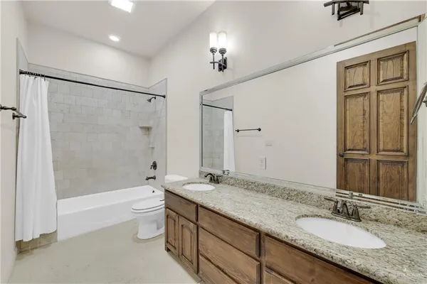 a bathroom with a granite countertop bathtub shower sink vanity and toilet
