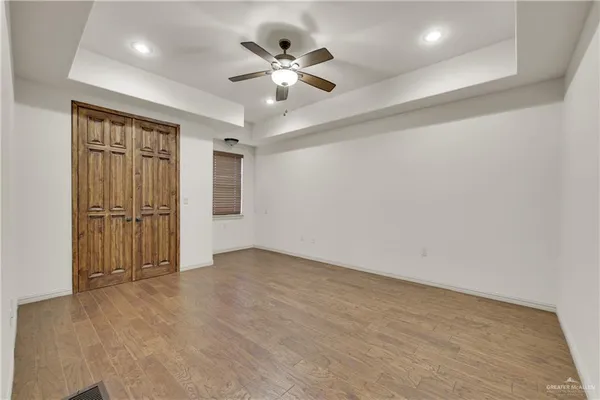 an empty room with ceiling fan and windows