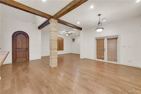 a view of an empty room with window and wooden floor