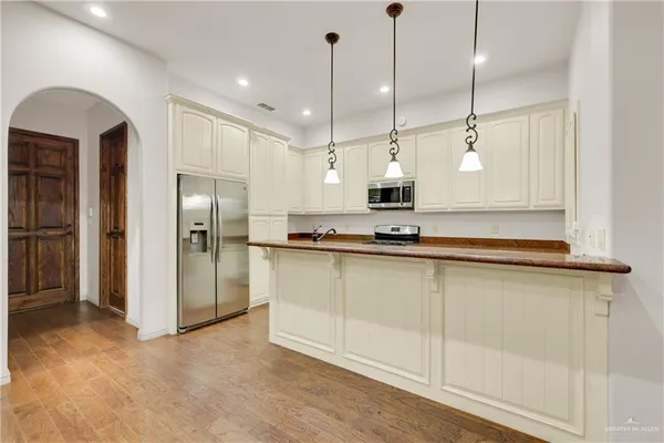 a open kitchen with stainless steel appliances granite countertop a refrigerator a sink and a chandelier
