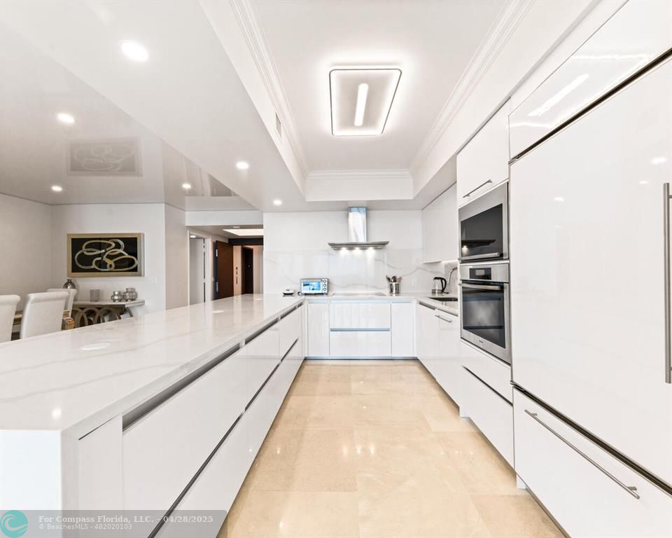 101 South Fort Lauderdale Beach Boulevard, Unit 1104 Fort Lauderdale, FL 33316 - Photo 5 of 41 a large white kitchen with kitchen island a large counter top space and stainless steel appliances