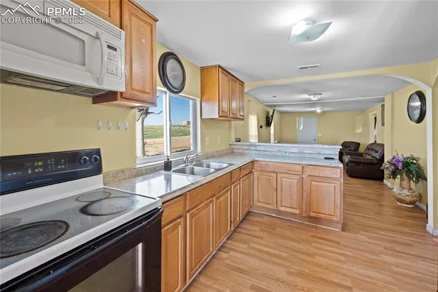 a large kitchen with stainless steel appliances granite countertop a stove and a wooden floors