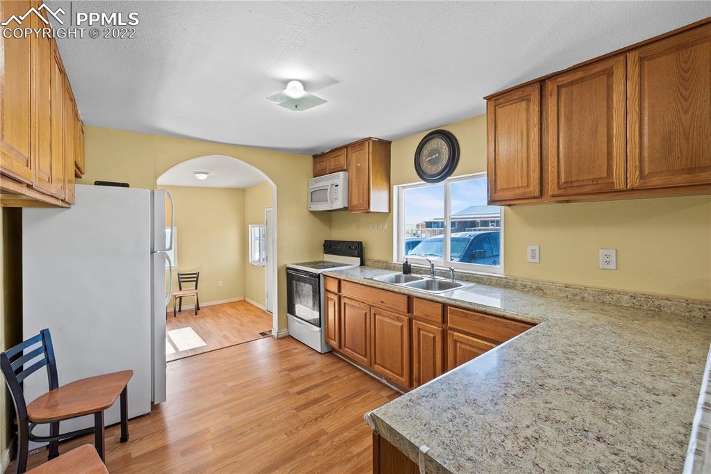 5025 Lauppe Road Yoder, CO 80864 - Photo 12 of 50 a kitchen with stainless steel appliances granite countertop a sink dishwasher stove and wooden cabinets