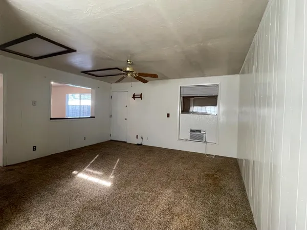 an empty room with a window and a fan
