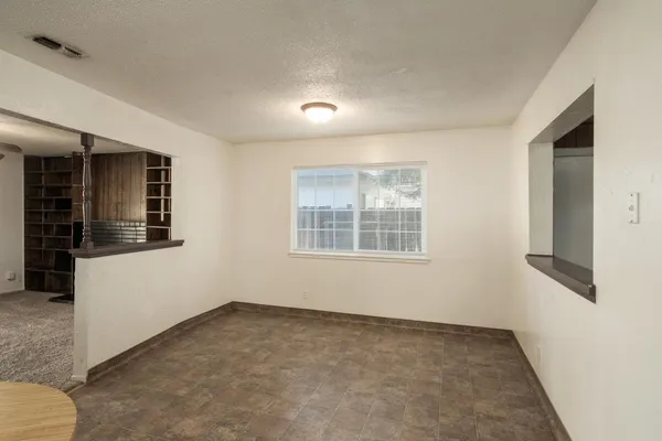 an empty room with a window and a fan