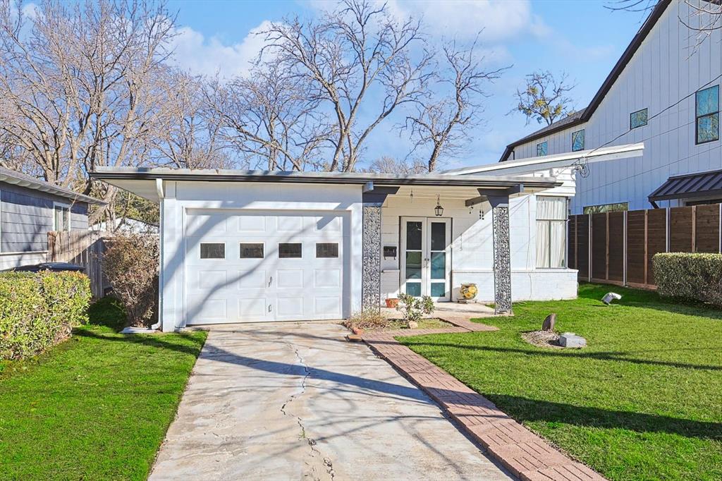 a view of a white house with a big yard and potted plants and large trees