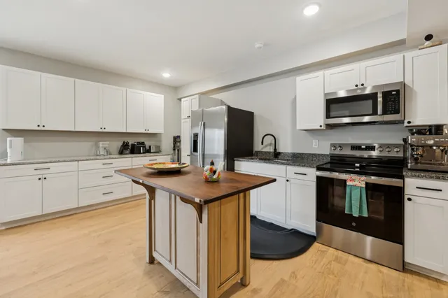 a kitchen with stainless steel appliances granite countertop a sink a stove top oven a counter space and cabinets