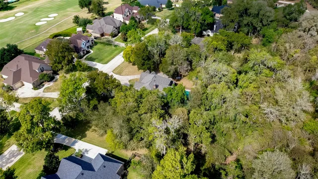 an aerial view of residential house with outdoor space and trees all around