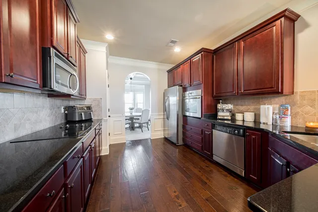 a kitchen with granite countertop wooden floors wooden cabinets and stainless steel appliances