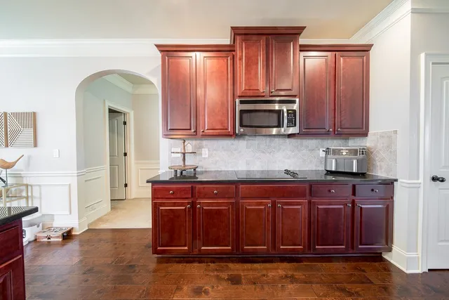 a kitchen with stainless steel appliances granite countertop a stove a sink dishwasher and cabinets with wooden floor