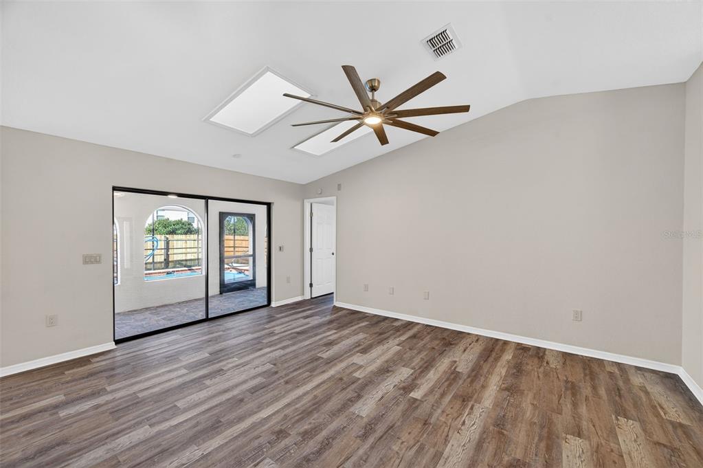 12435 Lola Drive Spring Hill, FL 34608 - Photo 12 of 63 an empty room with wooden floor ceiling fan and windows