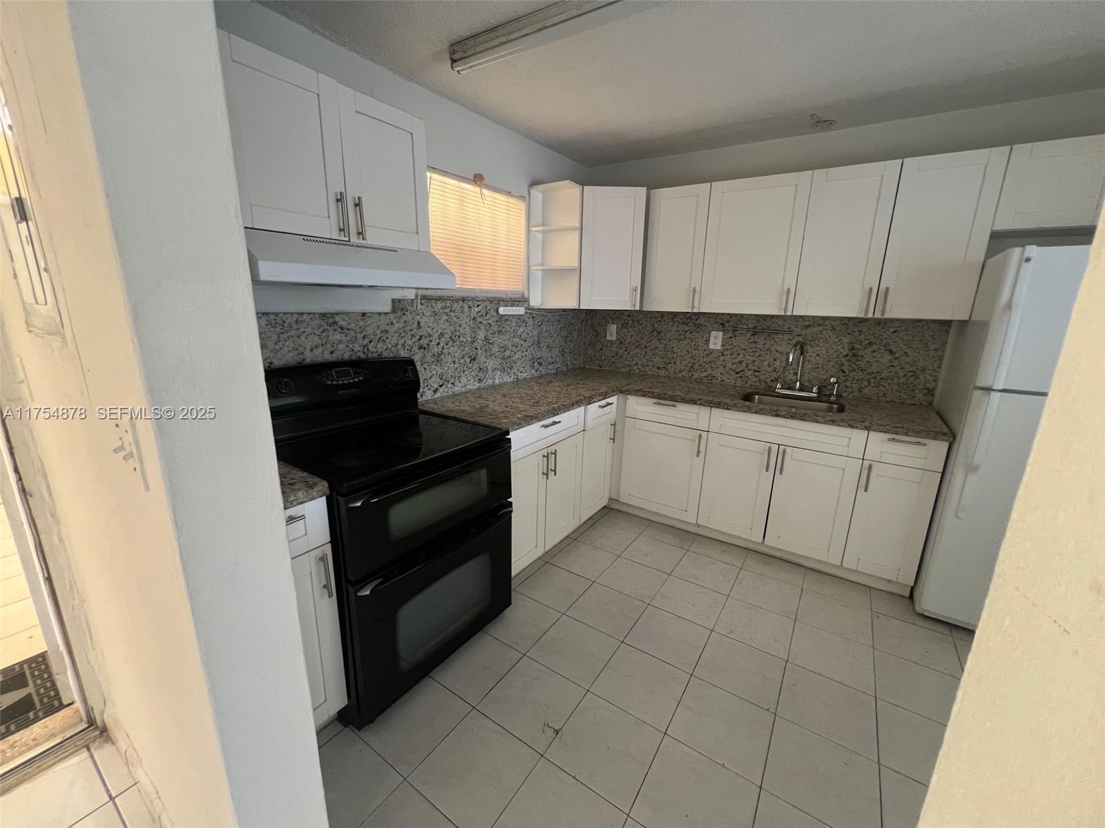887 West 29th Street, Unit 2 Hialeah, FL 33012 - Photo 7 of 10 a kitchen with granite countertop white cabinets and white appliances