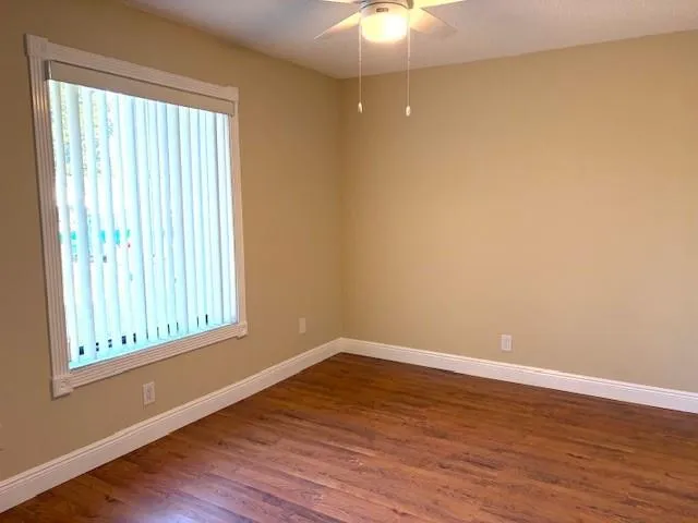 a view of an empty room with wooden floor and a window