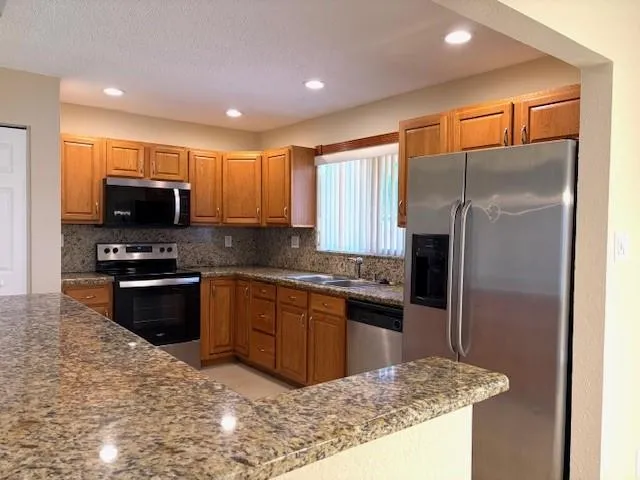 a kitchen with stainless steel appliances granite countertop a refrigerator and a stove top oven