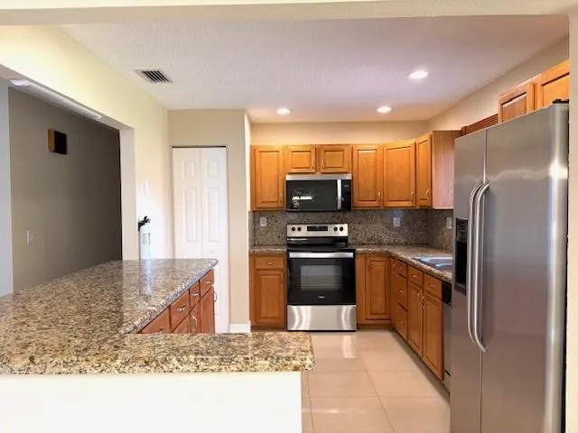 a kitchen with stainless steel appliances granite countertop a refrigerator a stove and a sink