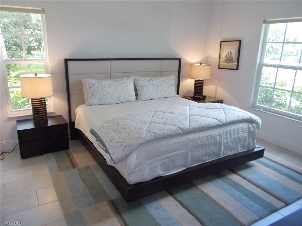847 Tanbark Drive, Unit 101 Naples, FL 34108 - Photo 6 of 11 a bedroom with a bed and wooden floor