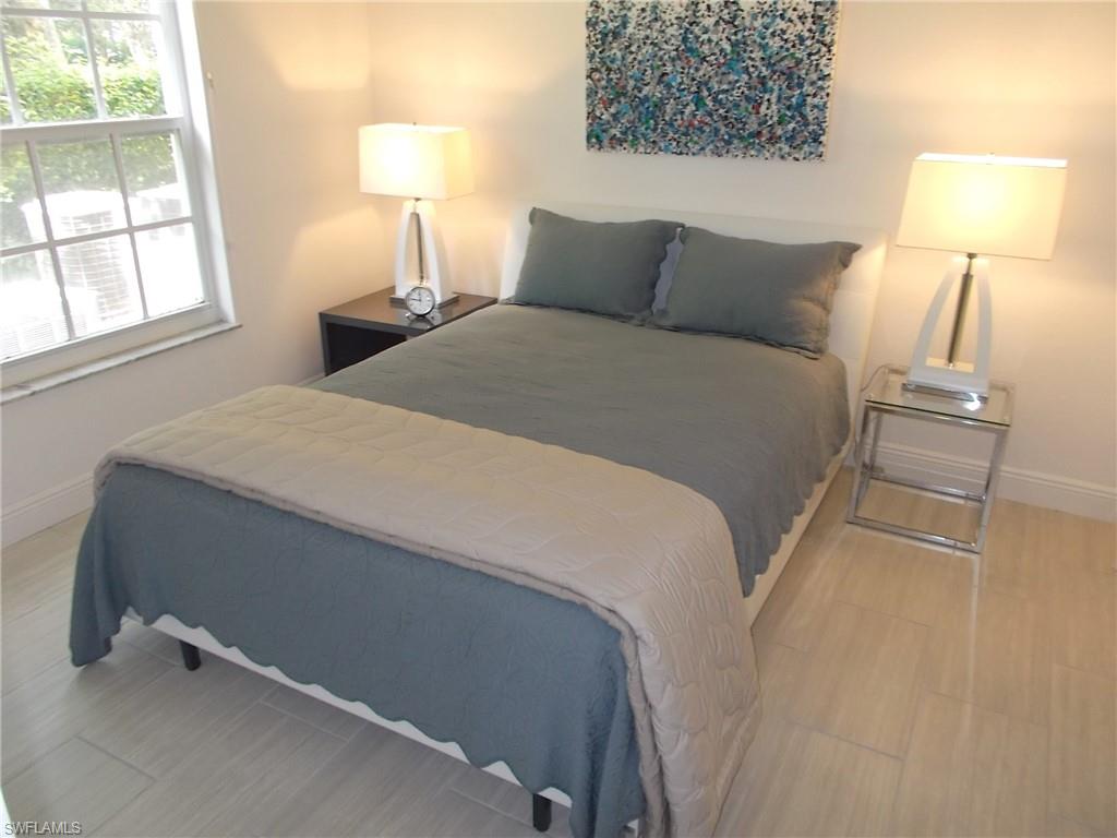 847 Tanbark Drive, Unit 101 Naples, FL 34108 - Photo 8 of 11 a bedroom with a bed and a lamp