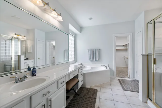 a spacious bathroom with a double vanity sink a mirror and a bathtub