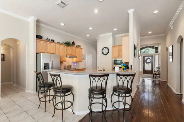 a dining room with stainless steel appliances kitchen island granite countertop a dining table chairs and a refrigerator