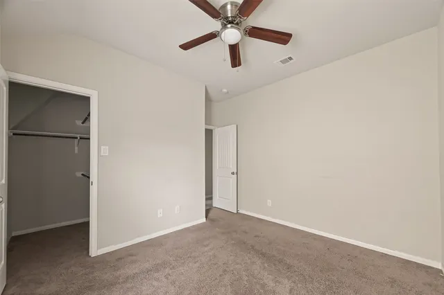 an empty room with closet and a chandelier fan
